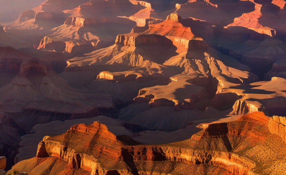 Panoramic view of the Grand Canyon at sunrise with a hiker on the South Rim.